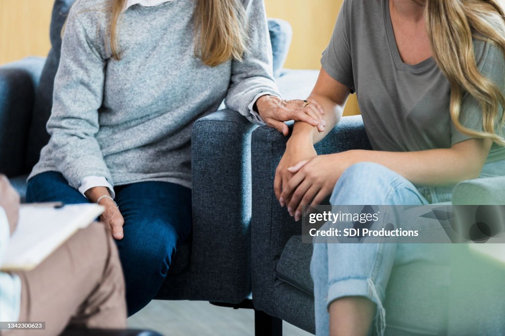 Unrecognizable mother and her teen daughter talk with counselor