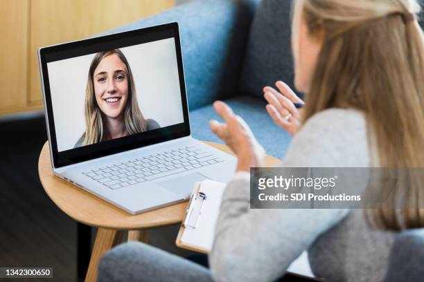therapist gives advice to young woman during online therapy session - mentoring virtual stock pictures, royalty-free photos & images
