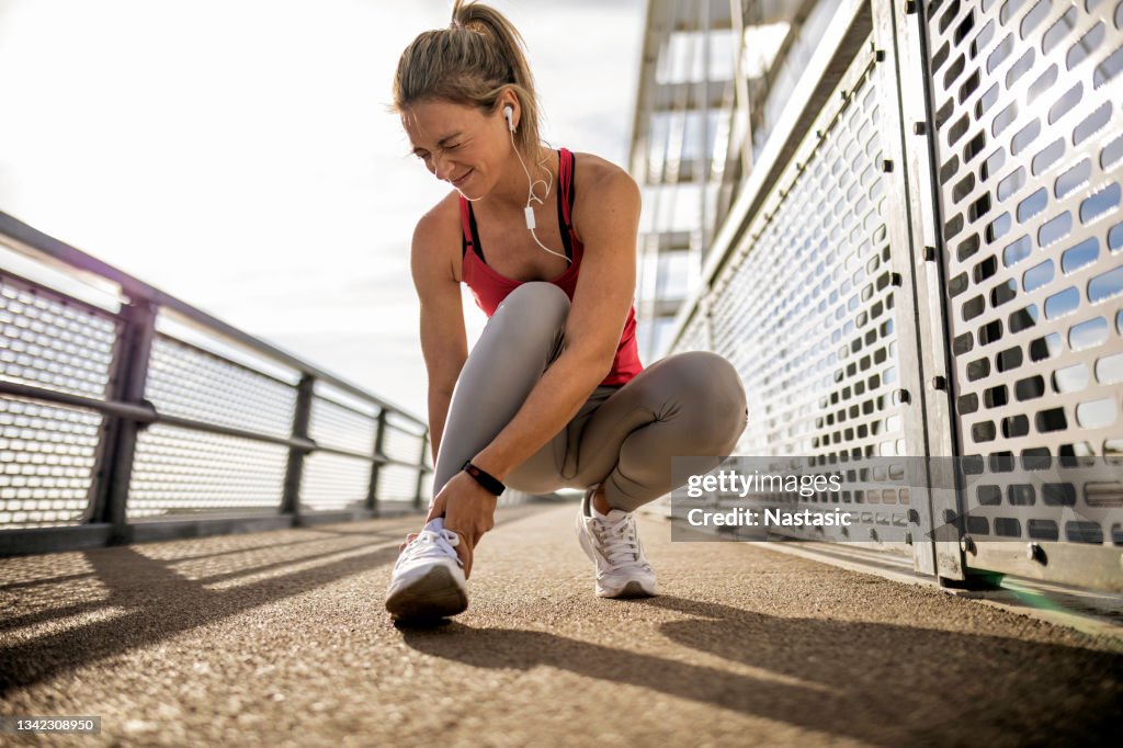 Deportista con tobillo lesionado haciendo una cara dolorosa