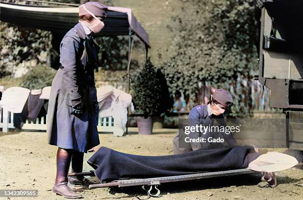 Red Cross volunteers conduct an ambulance demonstration while wearing cloth face masks during the 1918 influenza pandemic, Washington, DC, 1918....