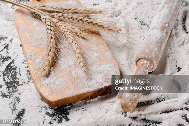 ears of wheat on flour next to a wooden dough mixer - ähren stock-fotos und bilder