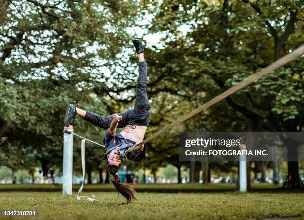 junger mann, der acro yoga auf slackline im park praktiziert - slackline stock-fotos und bilder