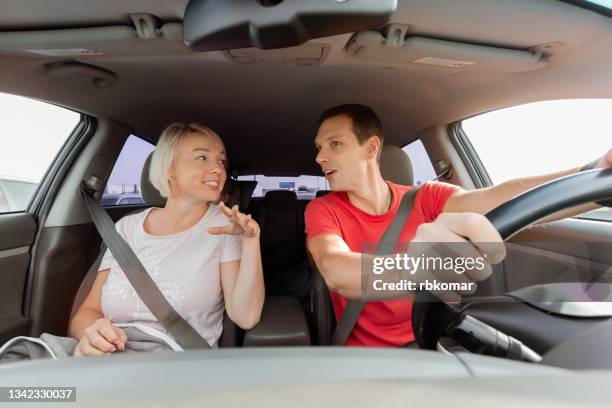young cheerful couple talking together while driving a car - conversation car bildbanksfoton och bilder