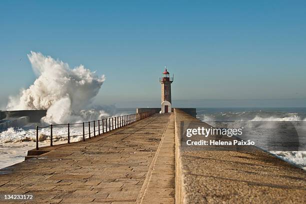 big wave crashing against pontoon plus lighthouse - pontonbrücke stock-fotos und bilder