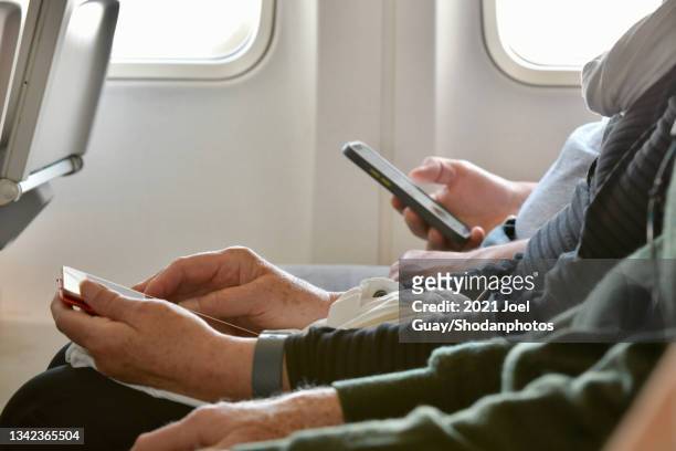 older person using smartphone on plane - aircraft wifi fotografías e imágenes de stock