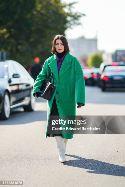 Alexandra Pereira wears a black turtleneck pullover, a neon purple wool polo shirt, a green ribbed velvet oversized long coat, a black shiny leather...