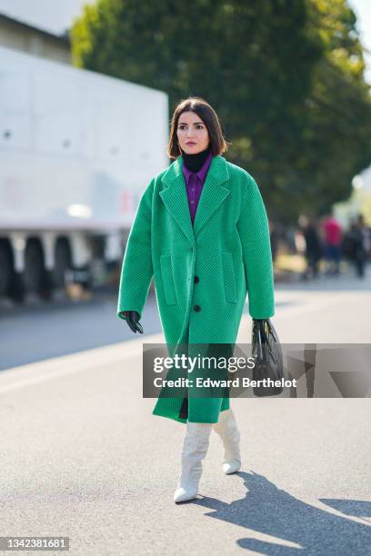 Alexandra Pereira wears a black turtleneck pullover, a neon purple wool polo shirt, a green ribbed velvet oversized long coat, a black shiny leather...