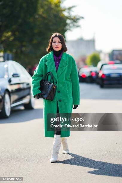 Alexandra Pereira wears a black turtleneck pullover, a neon purple wool polo shirt, a green ribbed velvet oversized long coat, a black shiny leather...