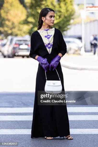 Camila Coelho, wearing black dress, purple gloves and white Prada bag, poses ahead of the Prada fashion show during the Milan Fashion Week - Spring /...