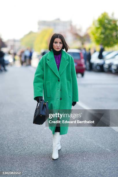 Alexandra Pereira wears a black turtleneck pullover, a neon purple wool polo shirt, a green ribbed velvet oversized long coat, a black shiny leather...