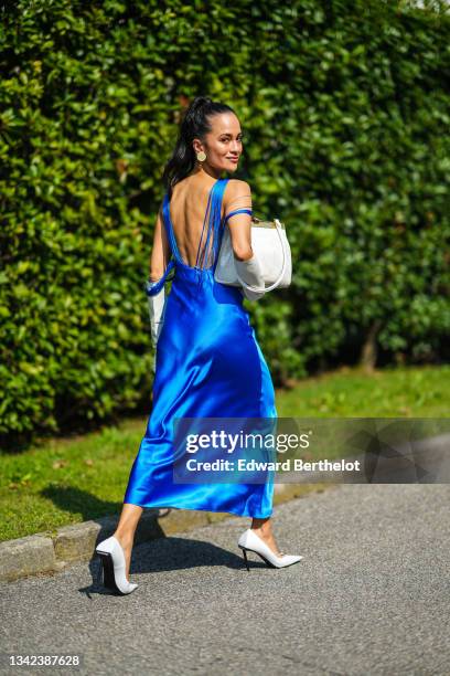 Anna Rosa Vitiello wears beige circle earrings, a royal blue fringed V-backless / asymmetric shoulders long flowing silk dress, white long gloves,...