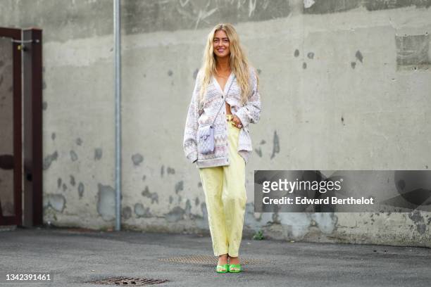 Emili Sindlev wears a white with red / yellow / purple print pattern wool long oversized cardigan, a pale purple shiny grained leather crossbody bag...