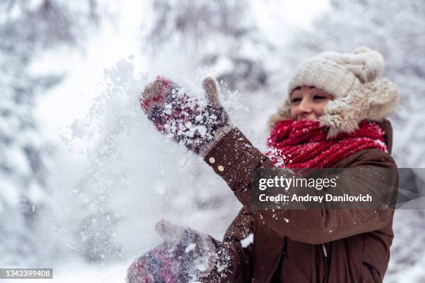 giovane donna che lancia neve in aria nella foresta invernale. - parka cappotto invernale foto e immagini stock