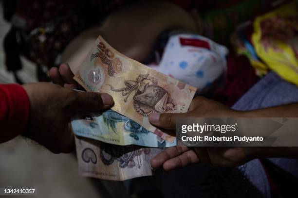 Man pays using Papua New Guinea Kina currency as he visit a traditional market near Skouw Cross Border Post on September 25, 2021 in Jayapura, Irian...