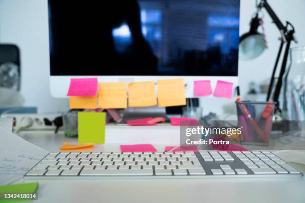 messy workstation in office with sticky notes on computer monitor - clutter stock pictures, royalty-free photos & images