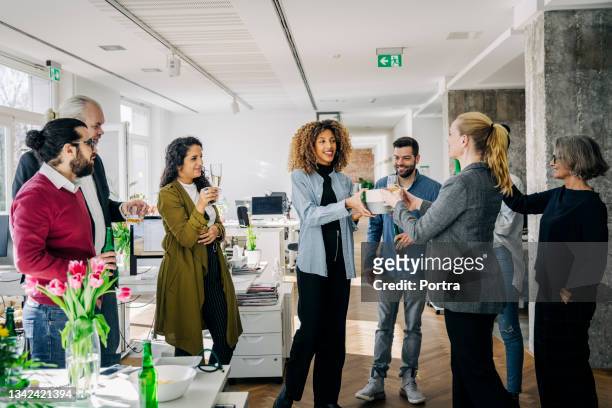 businesspeople giving a farewell party of a female colleague in office - the gift stock pictures, royalty-free photos & images