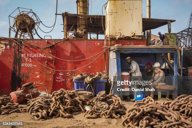 Laborers rest in an improvised shelter while taking a break from breaking down a decommissioned ship on September 20, 2021 in Gadani, Pakistan....