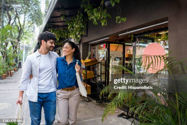 couple buying groceries at the local food market and using reusable bags - latin american and hispanic shopping bags stock pictures, royalty-free photos & images