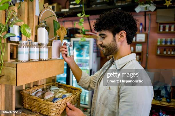 hombre comprando en un mercado orgánico y mirando suplementos - homeopatía fotografías e imágenes de stock