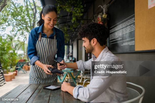 hombre haciendo un pago sin tapa en un restaurante usando su teléfono celular - credit card reader fotografías e imágenes de stock