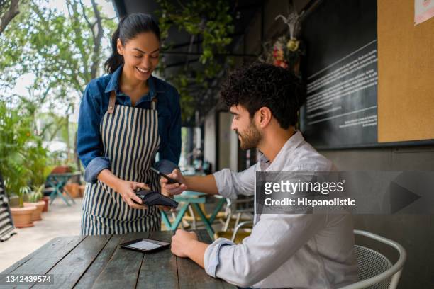 man making a contacless payment at a restaurant using his cell phone - bar code imagens e fotografias de stock