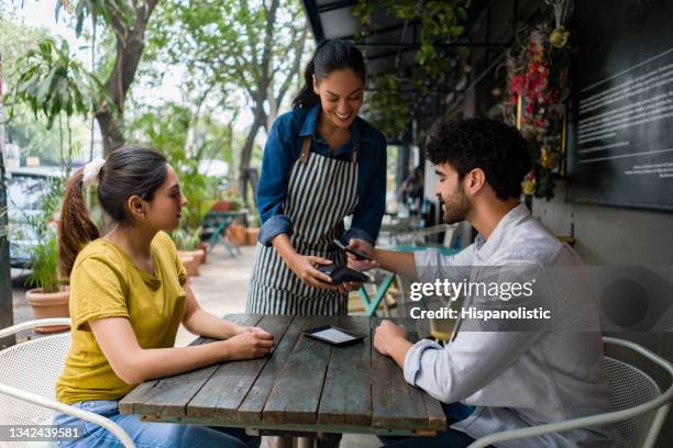 mann, der in einem café kontaktlos mit seinem handy bezahlt - pay restaurant stock-fotos und bilder