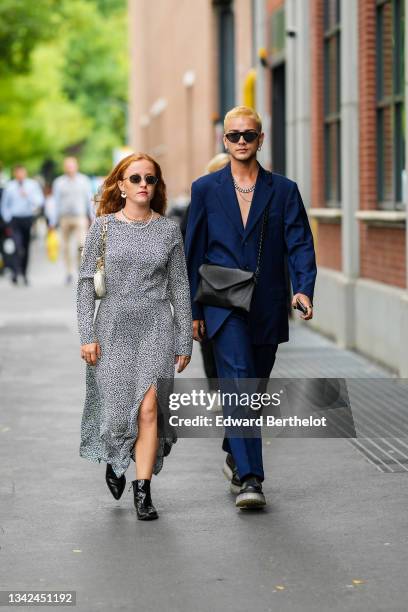 Guest wears sunglasses, gold pendant earrings, a gold chain necklace, a white pearls necklace, a black and white print pattern long sleeves slit /...