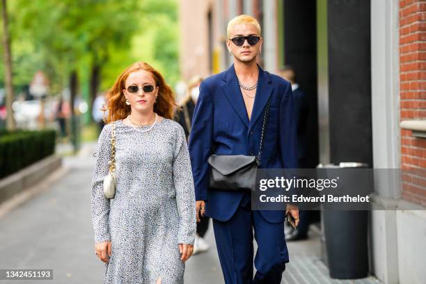 Guest wears sunglasses, gold pendant earrings, a gold chain necklace, a white pearls necklace, a black and white print pattern long sleeves slit /...