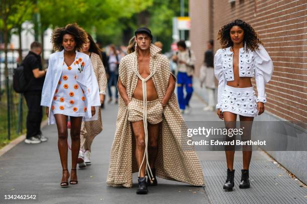 Guest wears a white with orange and green embroidered jacket, a matching white with orange embroidered flowers V-neck / short dress, black suede...