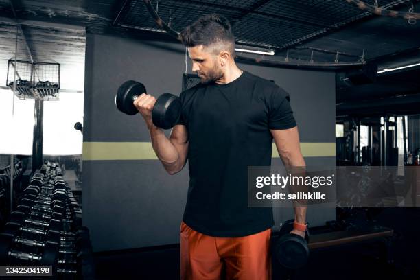 a man doing arm workout with dumbbell at gym - curled up stock pictures, royalty-free photos & images