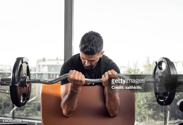 a man doing arm workout with barbell at gym. barbell biceps curl exercise - bicep curl stockfoto's en -beelden