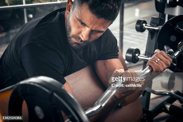 um homem fazendo exercício de braço com campainha na academia. exercício de bíceps de barbell - enroscado - fotografias e filmes do acervo