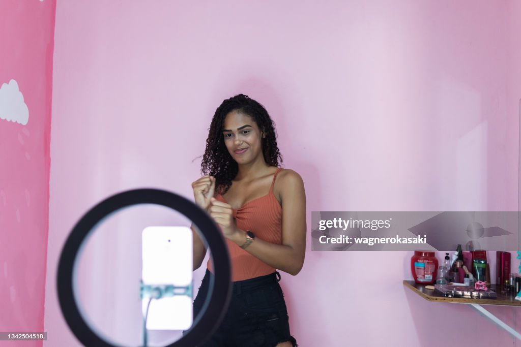 Black young woman filming herself dancing at home to share on social media