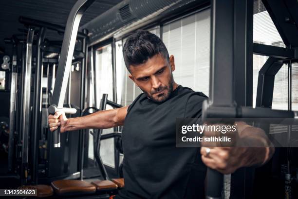 un hombre haciendo ejercicio de pecho con la máquina de moscas - chest fotografías e imágenes de stock