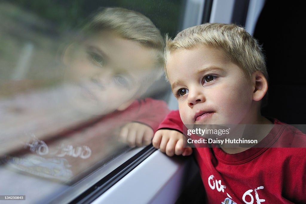 Young boy looking out of a train window