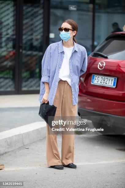 Guest outside Ports 1961 fashion show with an oversized striped shirt and brown pants during the Milan Fashion Week - Spring / Summer 2022 on...