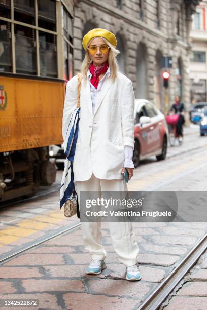 Guest outside Ermanno Scervino fashion show wearing a white pant suit, yellow berret, red bandana around the neck, orange sunglasses and Gucci bag...