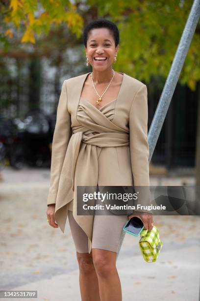 Tamu McPherson outside MSGM fashion show wearing a Petar Petrov light brown jacket, Frankie Shop shorts, MSGM clic bag, Amina Muaddi orange shoes and...