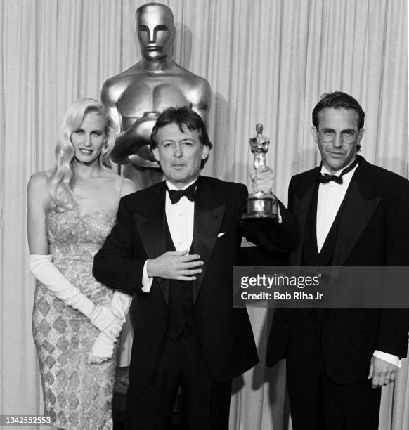 Oscar winner James Acheson with presenters Daryl Hannah and Kevin Costner backstage at the Academy Awards, April 11,1988 in Los Angeles, California.