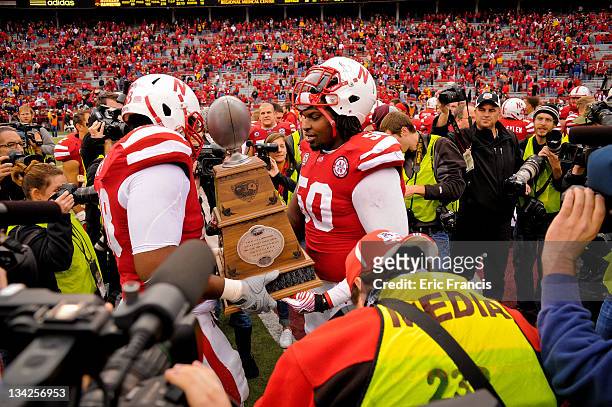 Offensive linesman Jermarcus Hardrick and offensive linesman Marcel Jones of the Nebraska Cornhuskers carry the Hero's Trophy of the field , awarded...