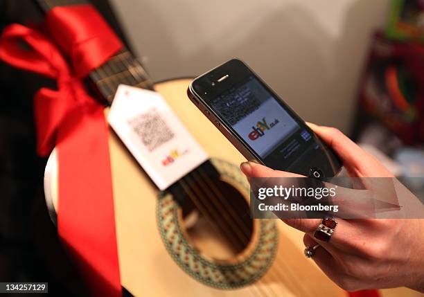 Customer uses an Apple Inc. IPhone 4 to scan a quick response code on a guitar at the EBay Inc. Christmas "pop-up" store in London, U.K., on Tuesday,...