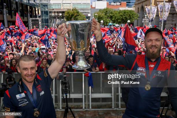 Simon Goodwin and Max Gawn of the Demons hold the 2021 AFL Premiership Cup aloft on stage at Forrest Place "Footy Place" on September 26, 2021 in...