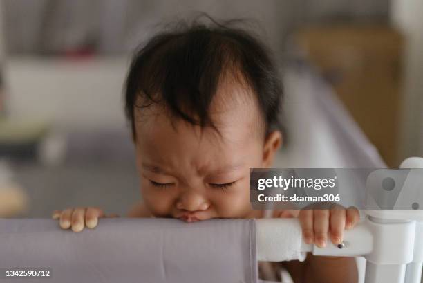 asian baby girl (4-7month)standing feeling negative emotion and crying and shouting in baby playpen fence - playpen stock pictures, royalty-free photos & images