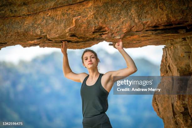 woman rock climber arms up holding cliff rocky overhang, mountain - rock overhang imagens e fotografias de stock