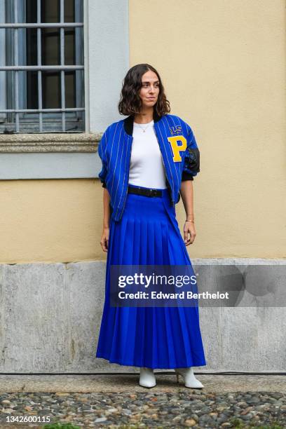 Erika Boldrin wears a royal blue electric with small yellow stripes sport bomber coat with a yellow embroidered P from Philosophy, a white ribbed...