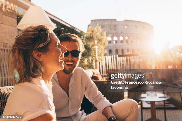 romantic couple having fun at sunset in rome, italy. colosseum and sunstar - italian foto e immagini stock