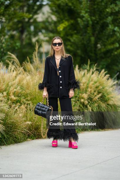 Julia Comil wears black sunglasses, gold and pearls earrings, a gold chain necklace, a blue faded V-neck cropped tank-top from Prada, a black long...