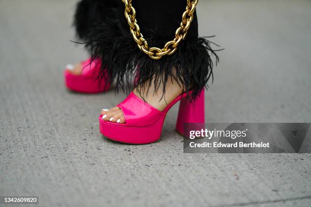 Julia Comil wears black large pants with feathers on the ankles, neon pink shiny leather block heels open toe-cap sandals, outside the MSGM fashion...