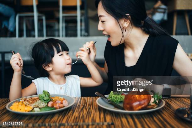 young asian family having lunch in cafe, mother sharing food to her little daughter and enjoying a happy meal together. family and eating out lifestyle - mother daughter brunch bildbanksfoton och bilder