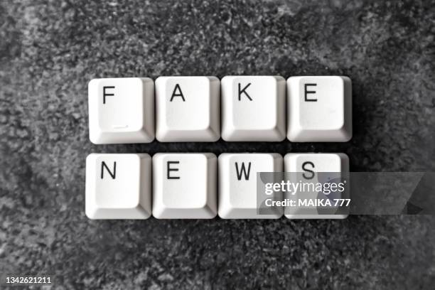 computer keyboard keys spelling the word fake news on black background. - fake news stock-fotos und bilder